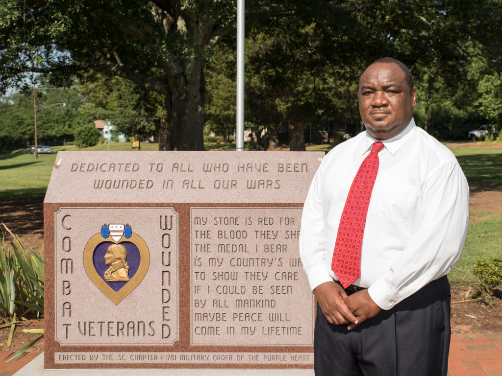 Photo of Mike Fowler in front of veteran memorial